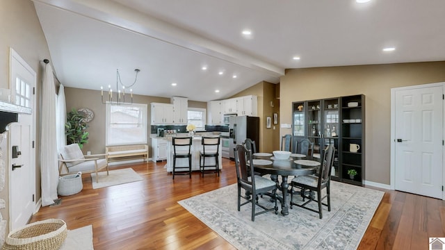 dining area featuring hardwood / wood-style flooring, lofted ceiling with beams, and a notable chandelier