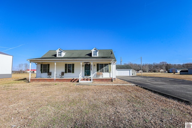 view of front facade with an outbuilding, a garage, covered porch, and a front lawn