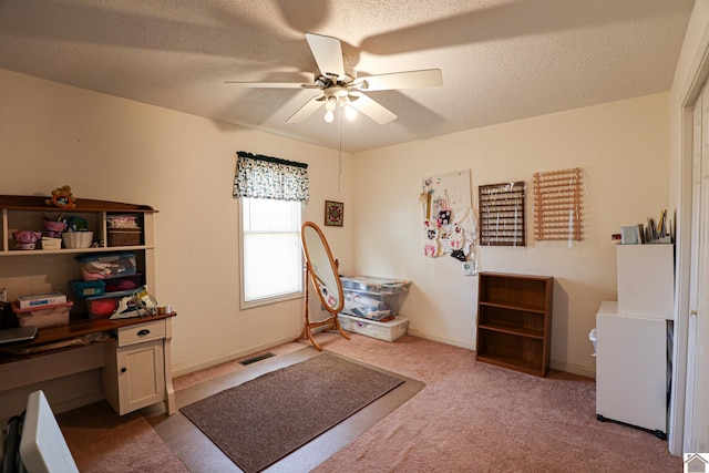 home office featuring light carpet, ceiling fan, and a textured ceiling