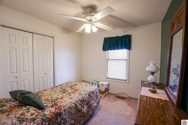 carpeted bedroom with ceiling fan, a textured ceiling, and a closet