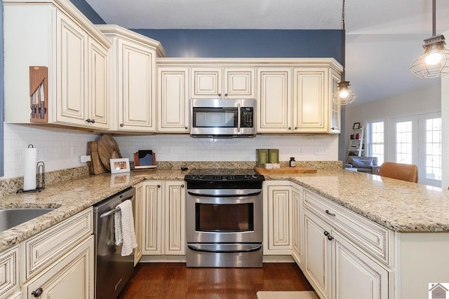 kitchen featuring dark hardwood / wood-style flooring, hanging light fixtures, cream cabinetry, and appliances with stainless steel finishes