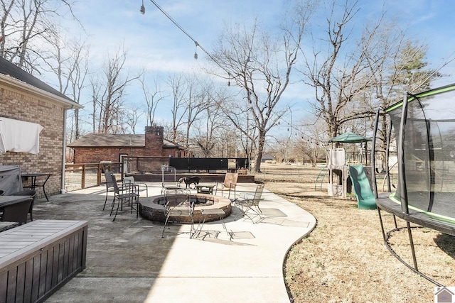 view of patio featuring an outdoor fire pit, a playground, and a trampoline