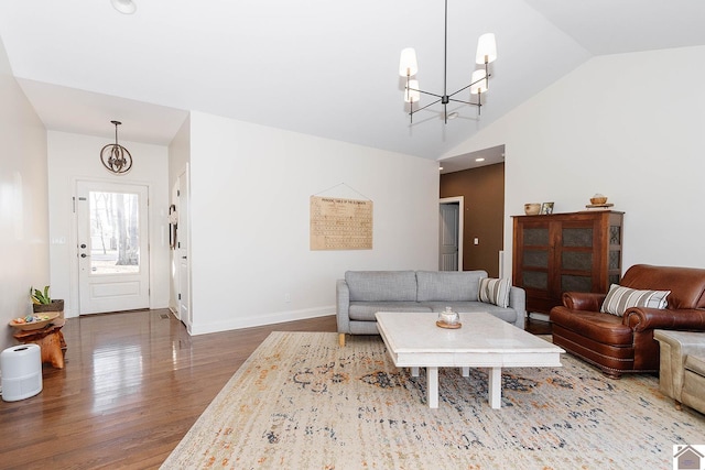 living room featuring hardwood / wood-style flooring, vaulted ceiling, and a notable chandelier