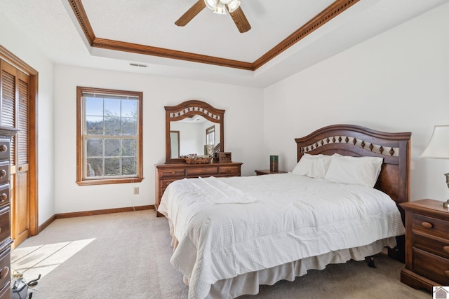 carpeted bedroom with ornamental molding, ceiling fan, and a tray ceiling