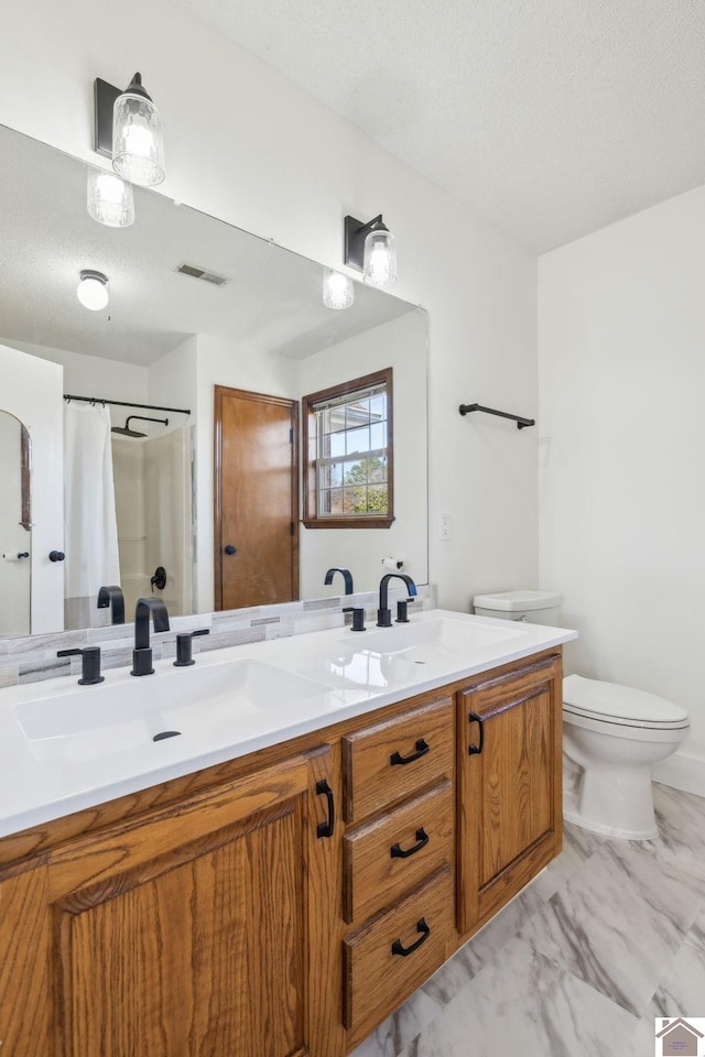 bathroom with vanity, curtained shower, toilet, and a textured ceiling