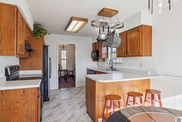 kitchen featuring kitchen peninsula, sink, a kitchen bar, black appliances, and plenty of natural light