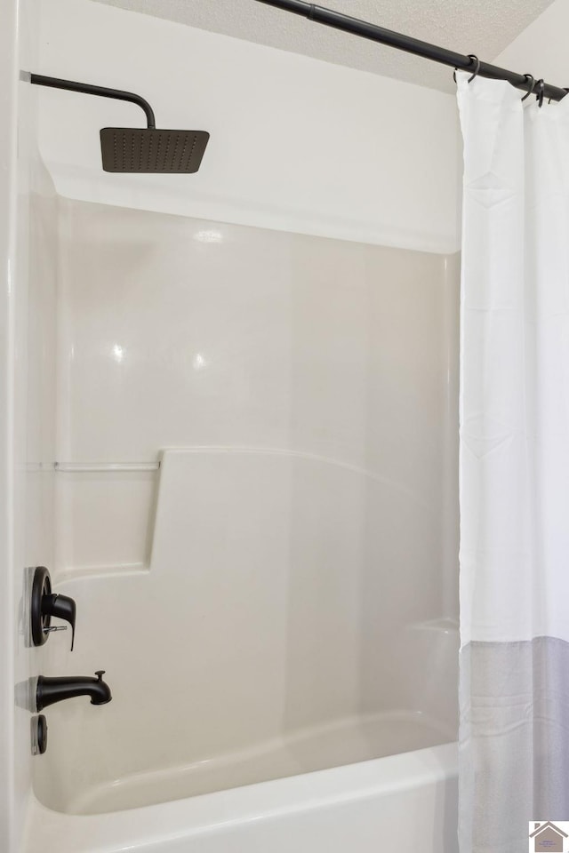 bathroom with shower / tub combo with curtain and a textured ceiling