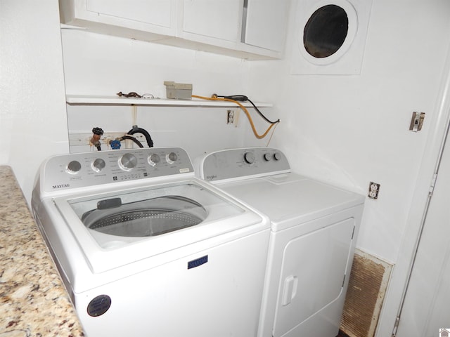 clothes washing area with cabinets and washer and clothes dryer