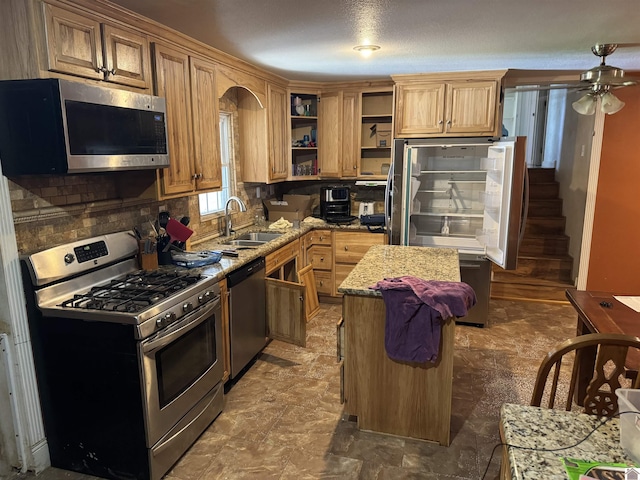 kitchen featuring a kitchen island, sink, backsplash, light stone counters, and stainless steel appliances