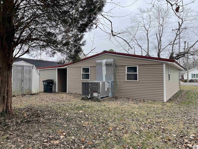 rear view of property featuring a shed and cooling unit