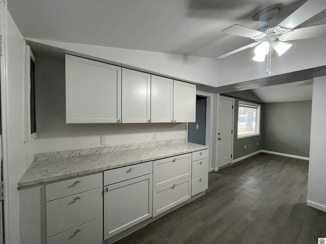 kitchen featuring lofted ceiling, dark hardwood / wood-style floors, light stone countertops, and white cabinets