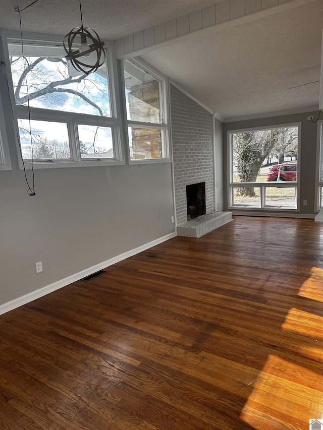 unfurnished living room with lofted ceiling, a brick fireplace, hardwood / wood-style flooring, and a textured ceiling