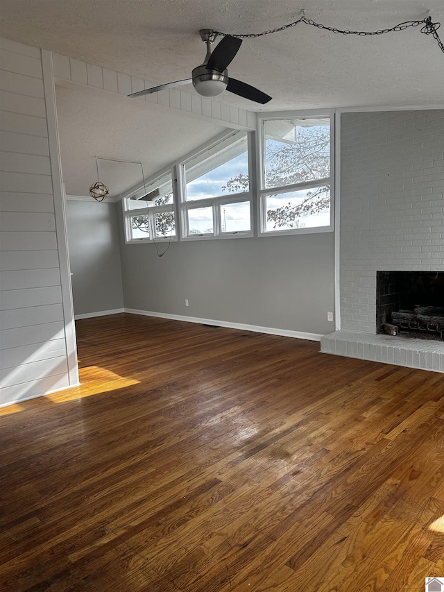 unfurnished living room featuring a brick fireplace, hardwood / wood-style floors, a textured ceiling, and ceiling fan