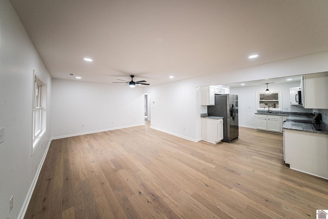 kitchen featuring light hardwood / wood-style flooring, ceiling fan, appliances with stainless steel finishes, white cabinetry, and dark stone counters