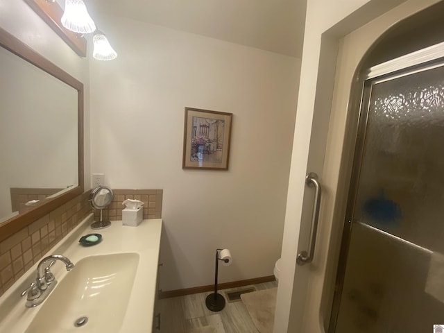 bathroom featuring tasteful backsplash, sink, a shower with door, and toilet