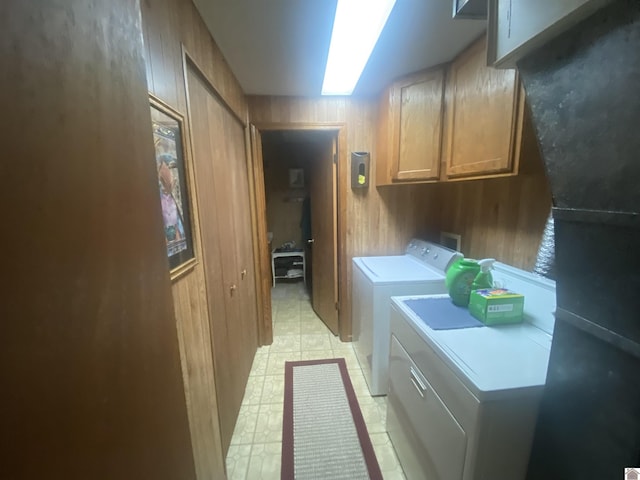 washroom featuring cabinets, a skylight, washing machine and dryer, and wood walls