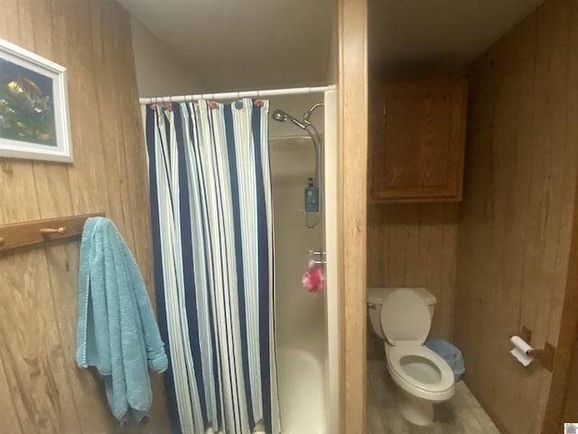 bathroom with a shower with curtain, wooden walls, and toilet