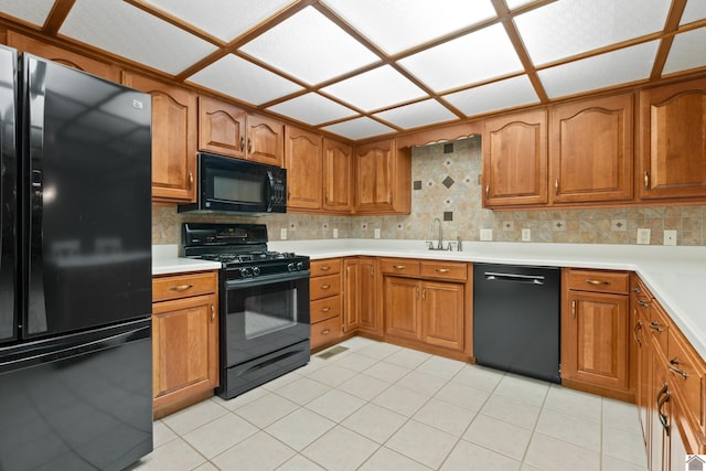 kitchen with tasteful backsplash, sink, light tile patterned floors, and black appliances