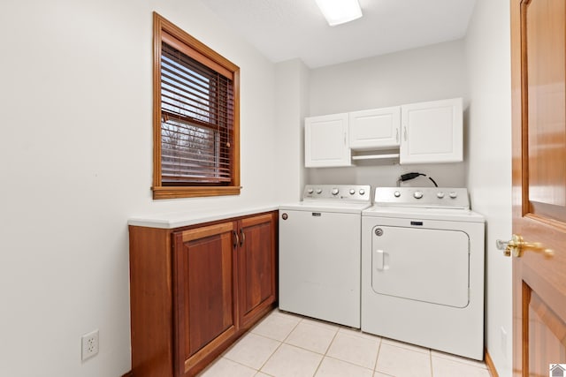 laundry area with washer and clothes dryer, cabinets, and light tile patterned flooring