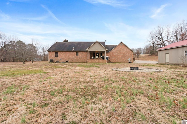 back of property featuring a lawn and an outdoor fire pit