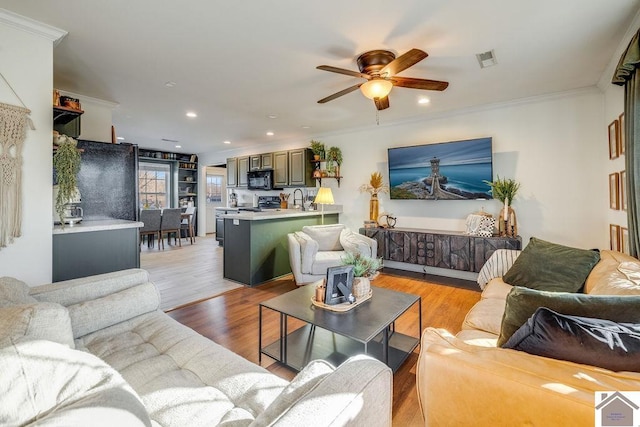 living room featuring crown molding, sink, ceiling fan, and light hardwood / wood-style flooring