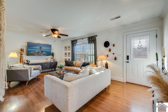 living room with wood-type flooring, ornamental molding, and ceiling fan