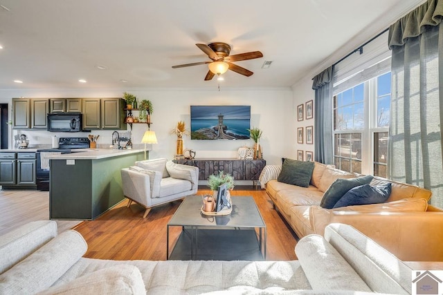 living room featuring ornamental molding, light hardwood / wood-style floors, and ceiling fan