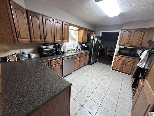 kitchen featuring stainless steel appliances, sink, a textured ceiling, and light tile patterned floors