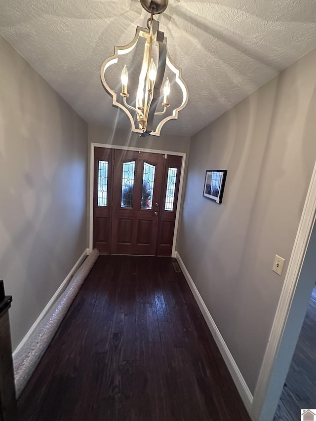 foyer with a notable chandelier, dark hardwood / wood-style floors, and a textured ceiling