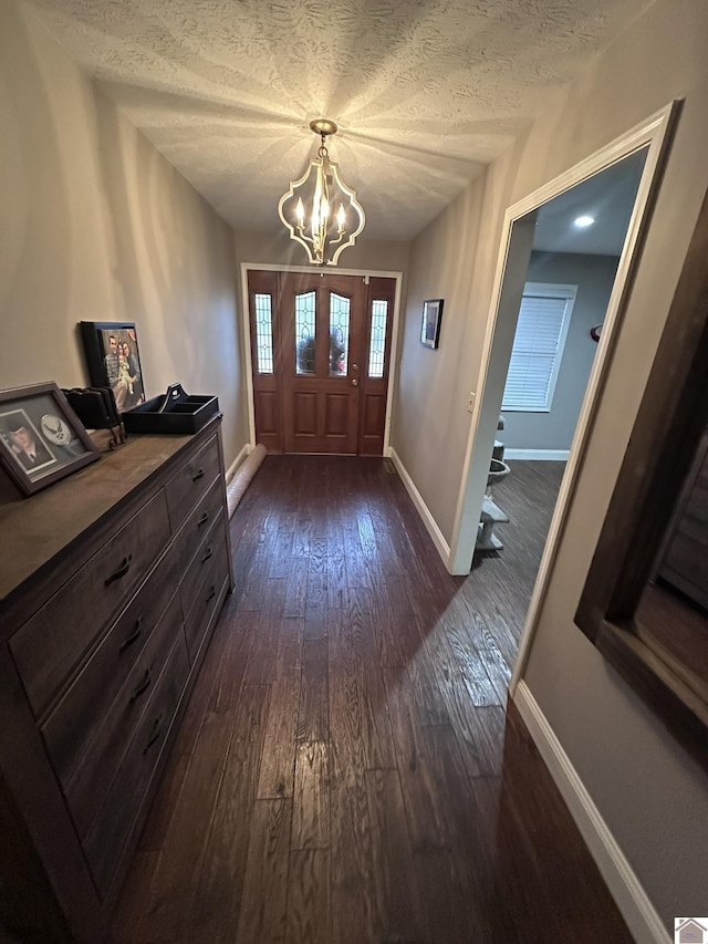 foyer with dark hardwood / wood-style floors, a chandelier, and a textured ceiling