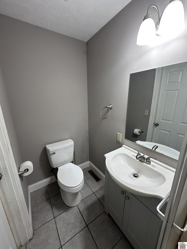 bathroom featuring tile patterned floors, vanity, toilet, and a textured ceiling