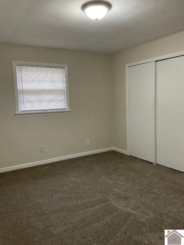 unfurnished bedroom featuring dark carpet and a closet