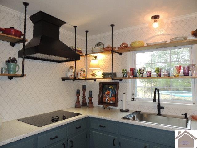 kitchen featuring pendant lighting, sink, crown molding, custom range hood, and black electric cooktop