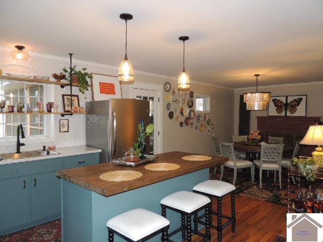 kitchen with pendant lighting, sink, blue cabinetry, and stainless steel refrigerator