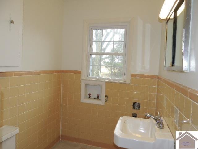 bathroom featuring tile walls, sink, and toilet