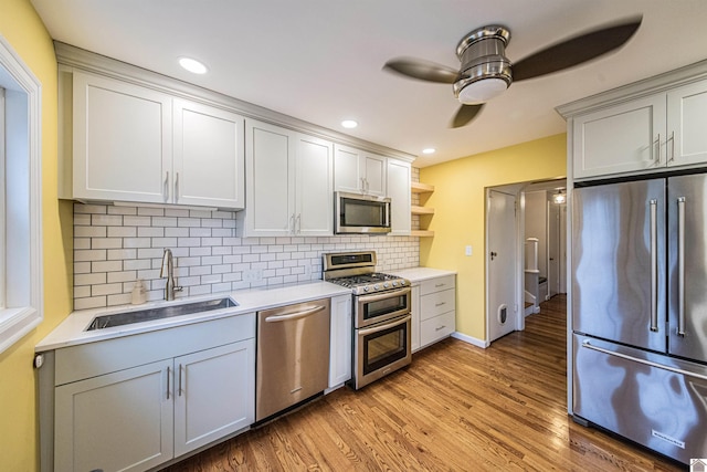 kitchen with sink, tasteful backsplash, light wood-type flooring, ceiling fan, and stainless steel appliances