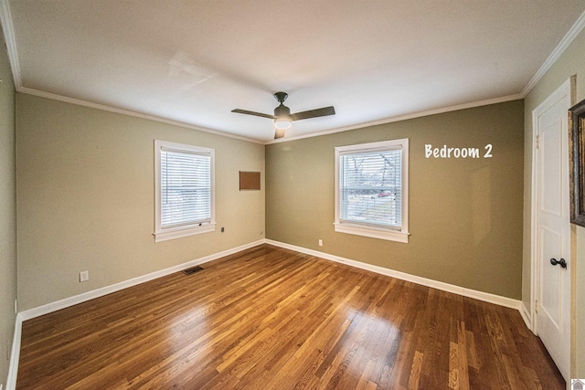 spare room with dark wood-type flooring, ornamental molding, and a wealth of natural light