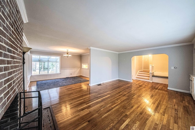 unfurnished living room with crown molding, a fireplace, dark hardwood / wood-style flooring, and a notable chandelier