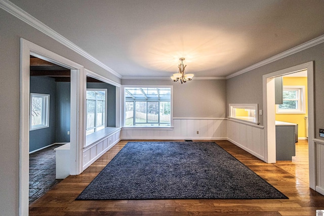 unfurnished dining area featuring crown molding, an inviting chandelier, and dark hardwood / wood-style flooring