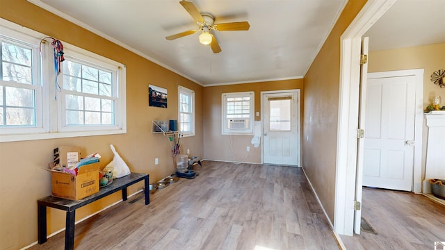 foyer entrance with crown molding, ceiling fan, cooling unit, and light wood-type flooring