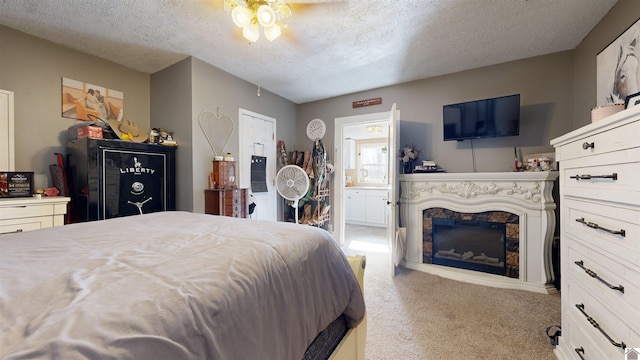 bedroom with ceiling fan, light colored carpet, a textured ceiling, and ensuite bath