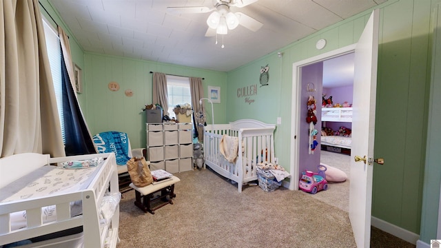 carpeted bedroom with a nursery area and ceiling fan