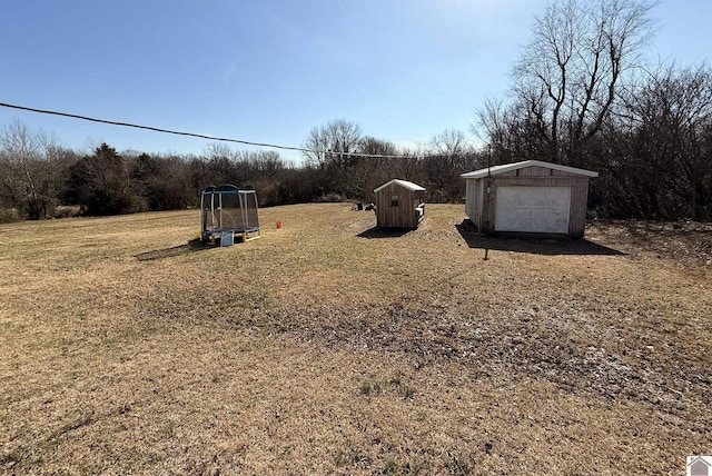 view of yard with a garage, a trampoline, and a storage shed