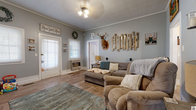 living room featuring crown molding, plenty of natural light, heating unit, and light hardwood / wood-style flooring