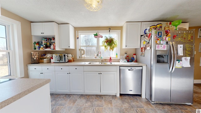 kitchen featuring stainless steel appliances, white cabinetry, sink, and a textured ceiling