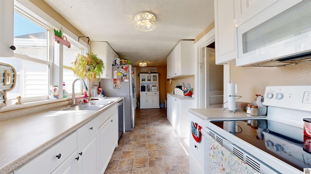 kitchen featuring appliances with stainless steel finishes, sink, white cabinets, and a textured ceiling