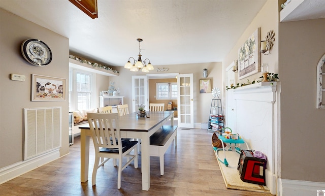 dining space with an inviting chandelier, light hardwood / wood-style flooring, and french doors