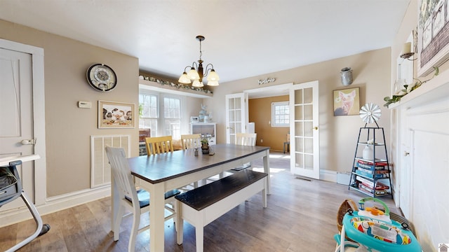 dining space featuring an inviting chandelier, light hardwood / wood-style floors, and french doors