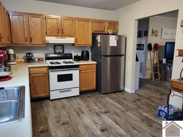 kitchen featuring freestanding refrigerator, white gas range, light countertops, under cabinet range hood, and a sink