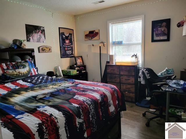 bedroom with light wood-style floors and visible vents